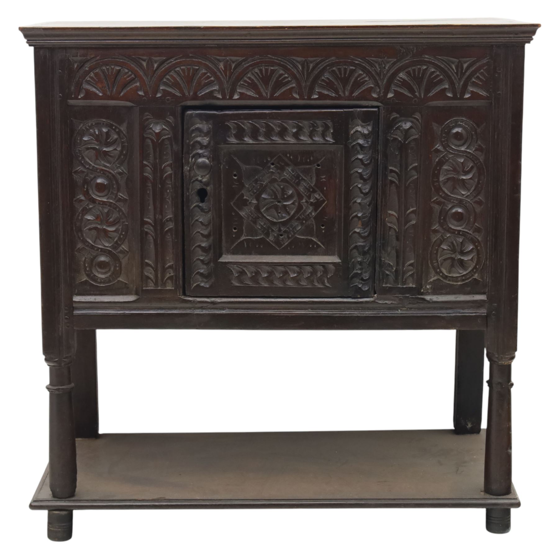 19th century oak cupboard cabinet, the moulded rectangular top above a deeply carved front carved with frieze of lunettes above a central panelled cupboard door with lozenge and foliate carving, flanked by vertical carved panels, upon turned legs with boarded lower shelf