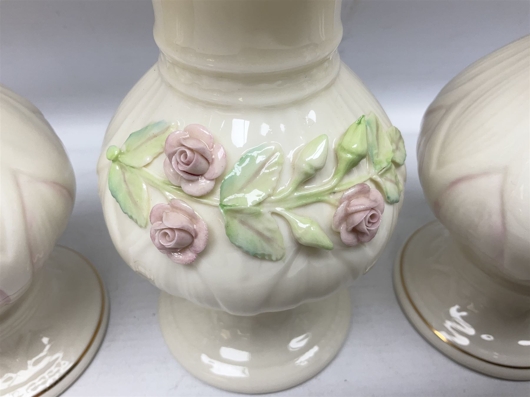 Five late 19th/early 20th century and later Belleek vases, comprising pair of Lotus Blossom examples, shamrock tree trunk vase, twin handled shamrock vase and a baluster form vase decorated with applied roses, all with printed marks beneath, tallest H16cm