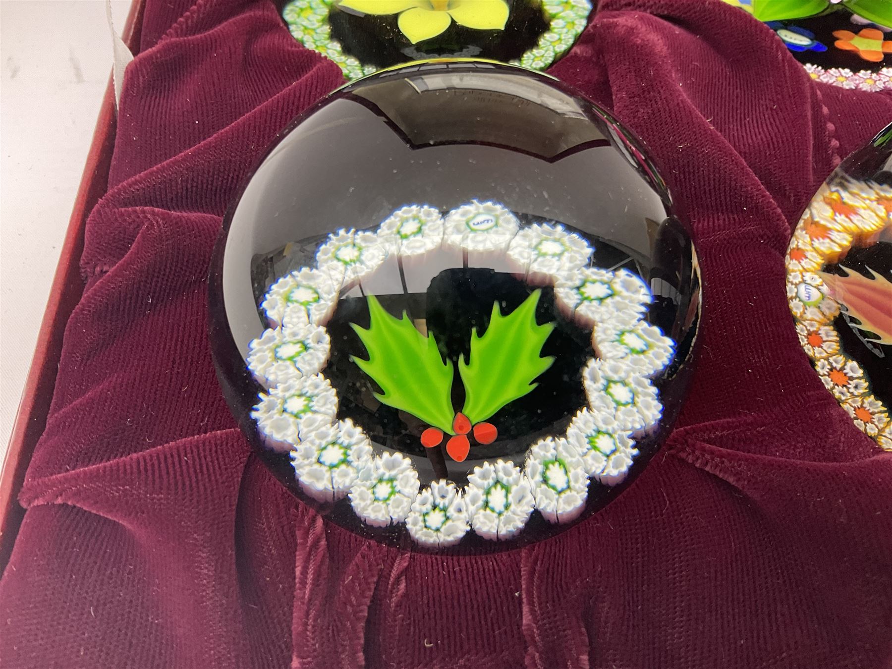 Set of four Caithness paperweights titled Four Seasons, in presentation box with certificate, designed by Colin Terris and made by William Mason, each internally decorated with a seasonal flower within a millefiori cane work garland, numbered 128 of 500
