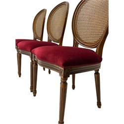Set six French style walnut finish dining chairs, oval cane bergere backs over serpentine seats upholstered in red, flower head carved fluted supports