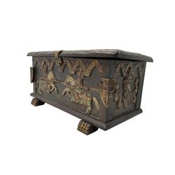 Carved wooden blanket chest, the tooled hinged lid with shaped metal strap hinges and catch, the front carved with arcade over two medieval jousters, on carved sledge feet