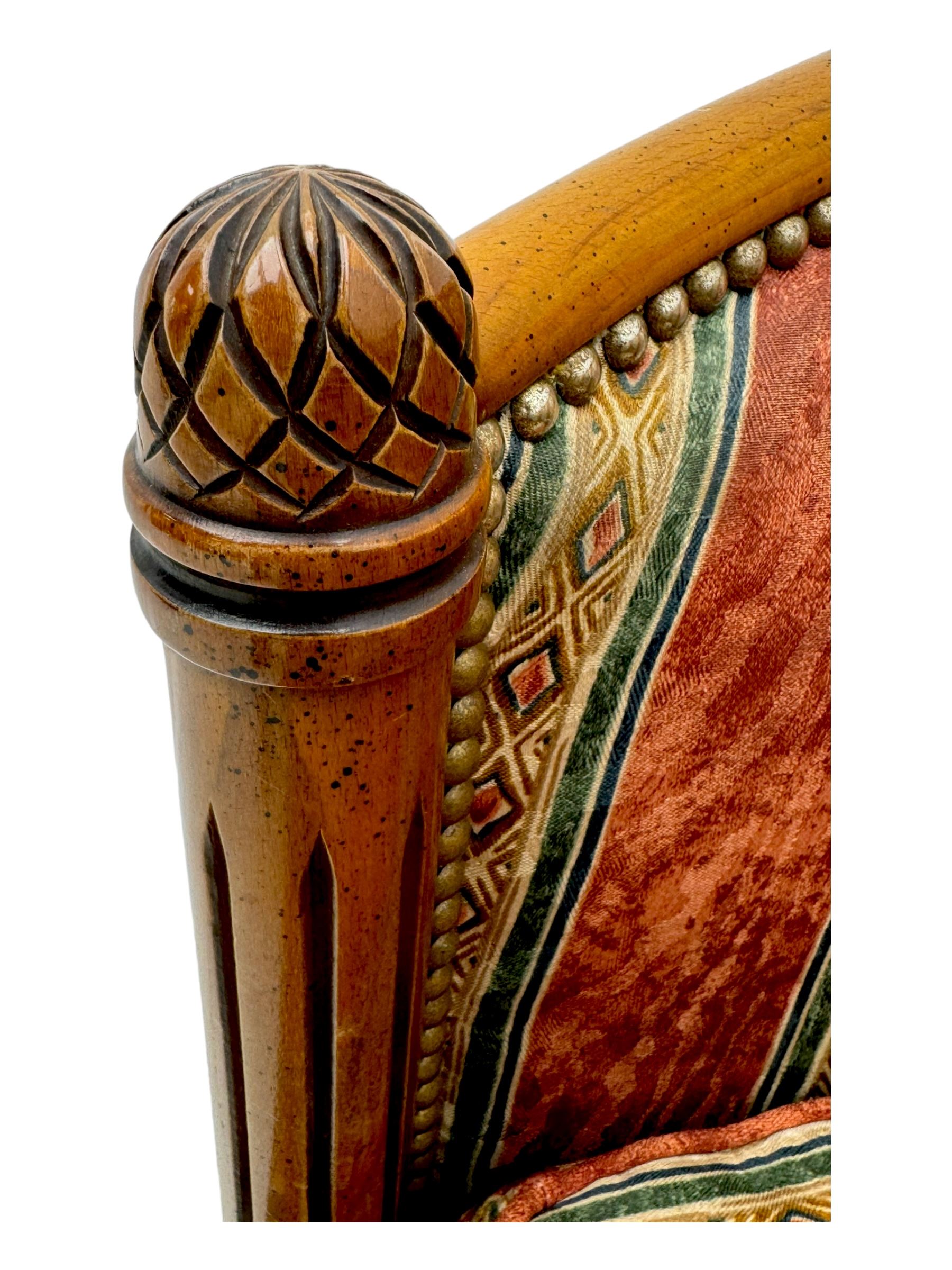 Pair of cherry wood framed tub-shaped armchairs, upholstered in striped floral fabric with brass stud trim, carved walnut frame with fluted supports capped with pinecone finials, on turned feet