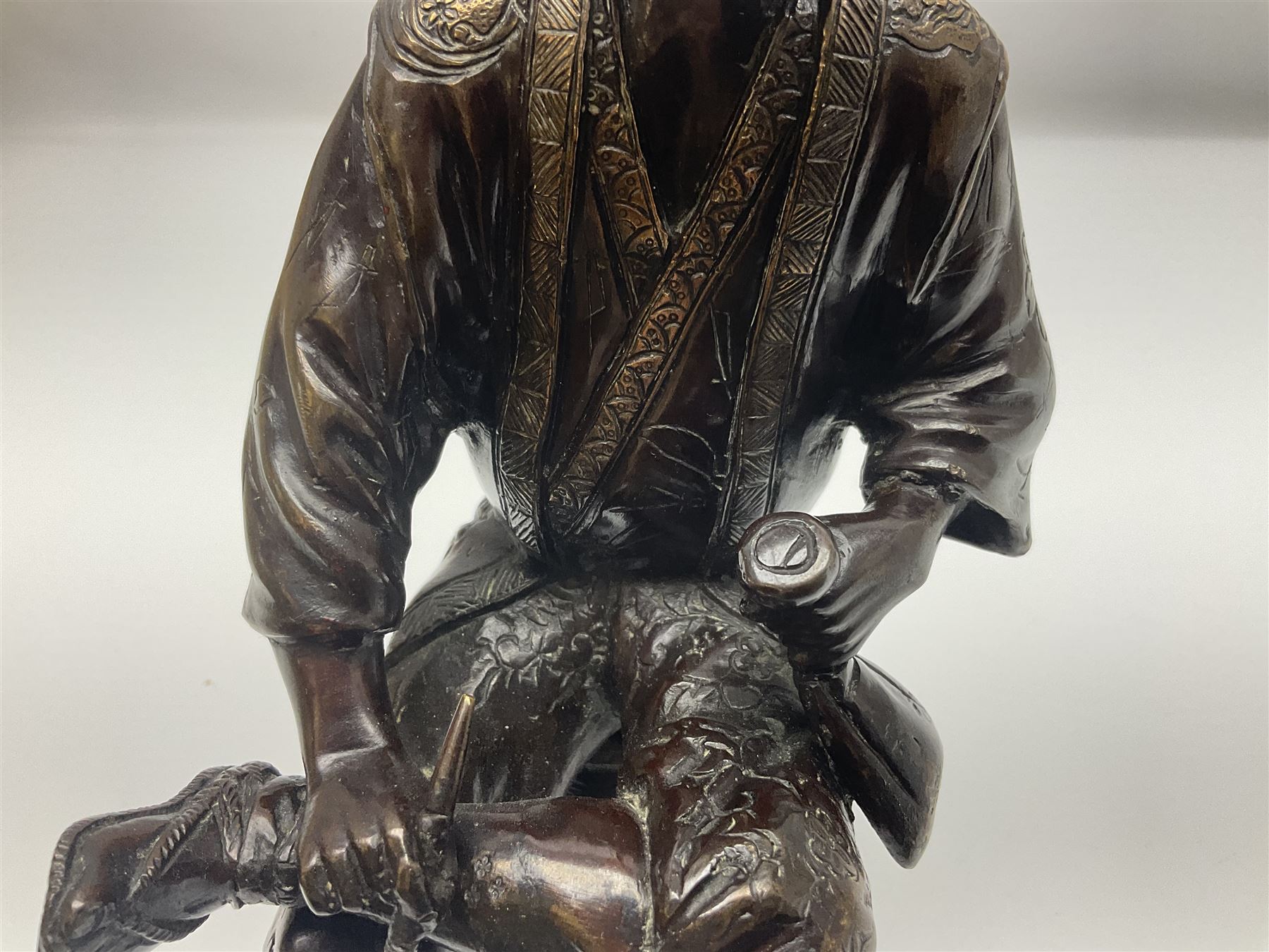Oriental bronze figure of a gentleman, modelled seated upon barrel with a pipe in one hand and a flask in the other, H21cm