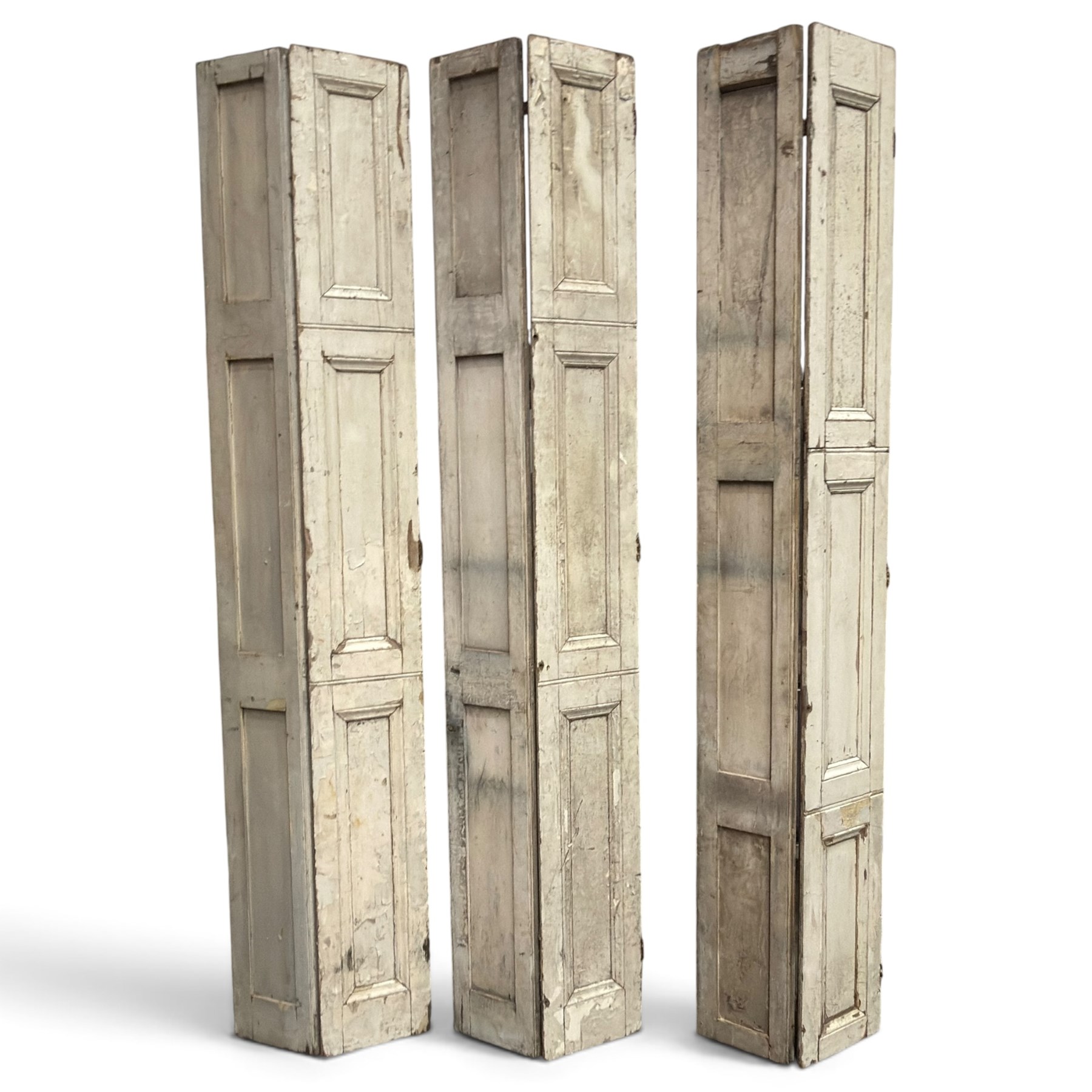 Set of three French 19th century painted pine folding window shutters of tall form, each comprising two hinged leaves with three graduated raised and fielded panels, in antique cream-painted finish