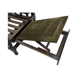 Late Victorian oak steamer chair, adjustable slatted backrest with grooved crest rail, wide armrests extending to a sliding adjustable footrest, open frame sides with vertical slats, side magazine rack and collapsible table, raised on turned front supports