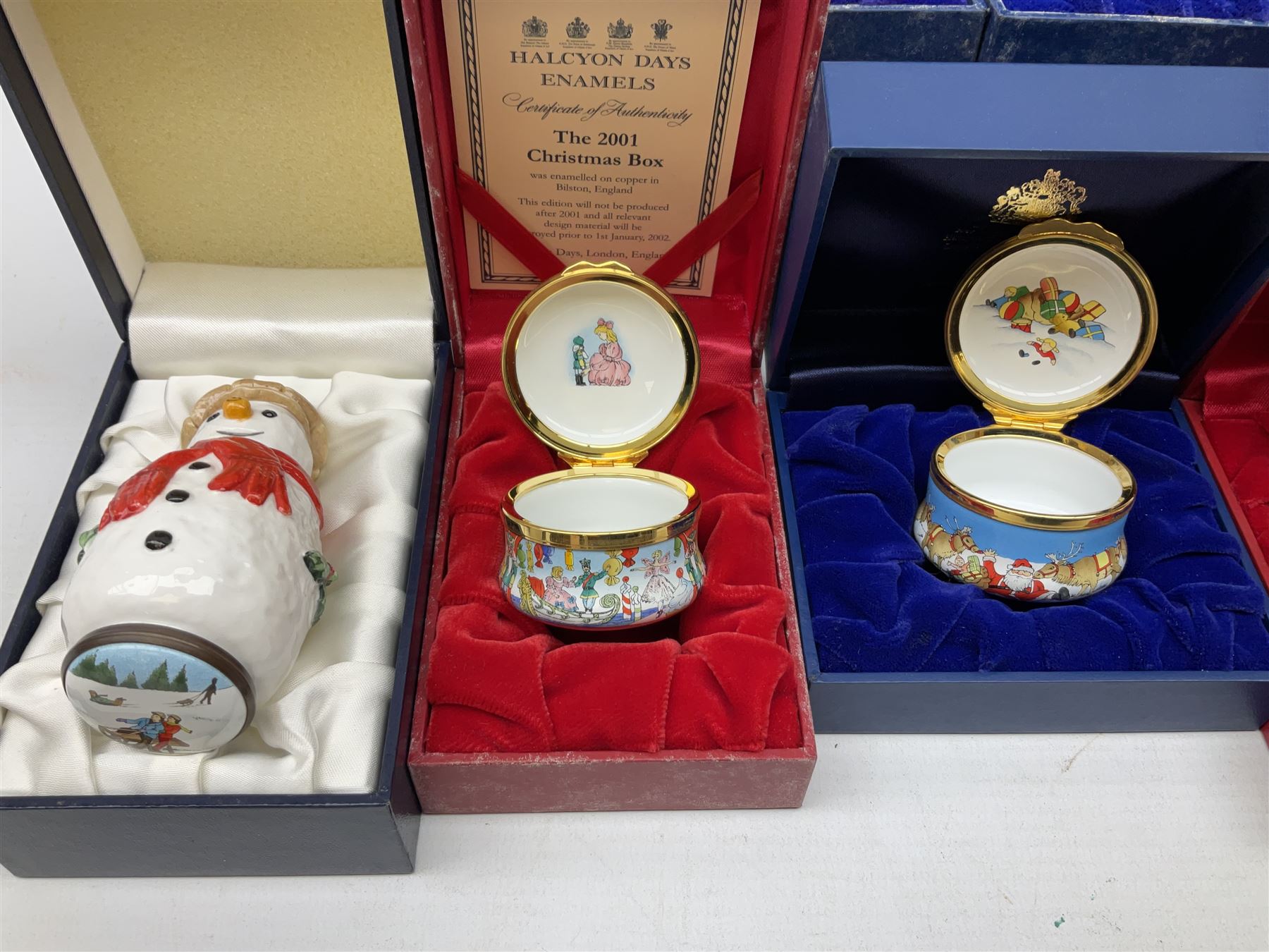 Eight Christmas themed Halcyon Days enamel boxes, and a Halcyon Days enamel bonbonniere modelled as a snowman, each in fitted box 