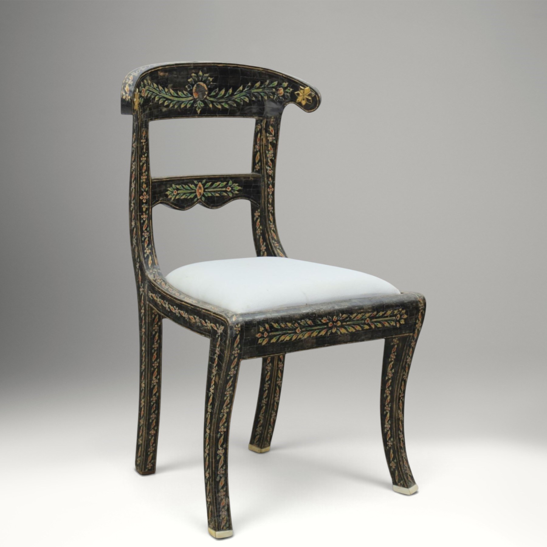 Early 20th century Anglo-Indian painted and inlaid armchairs, each with shaped top rail decorated with polychrome floral motifs above turned spindle galleries, shaped open arms and upholstered seats, on square supports with similar painted decoration