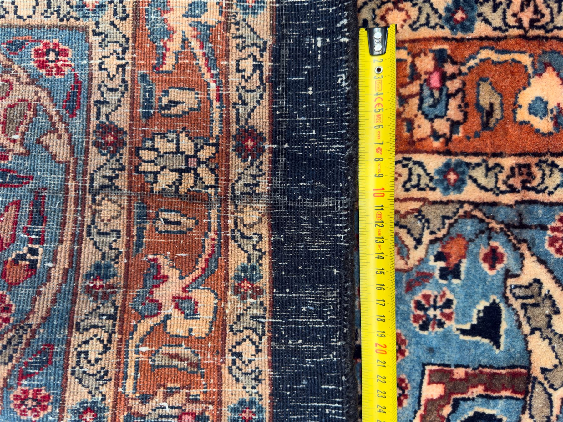 Northeastern Persian Meshed carpet, the deep navy field with a symmetrical floral arrangement of stylised flowerheads, palmettes and scrolling vines issuing from a central urn, enclosed by broad rust and blue borders of floral arabesques and lotus forms, from the region of Meshed