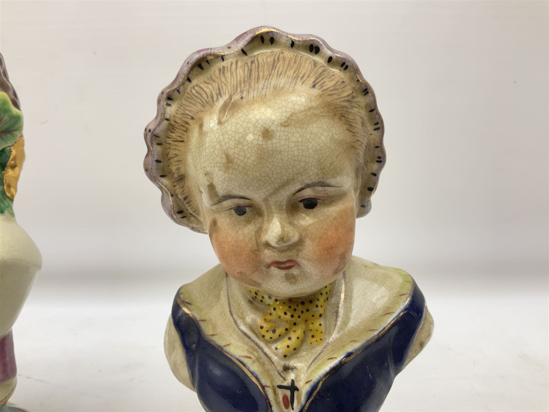 19th century pair of hand painted ceramic busts of children, together with a third similar example of a putti with a crown of ivy, tallest H23cm 