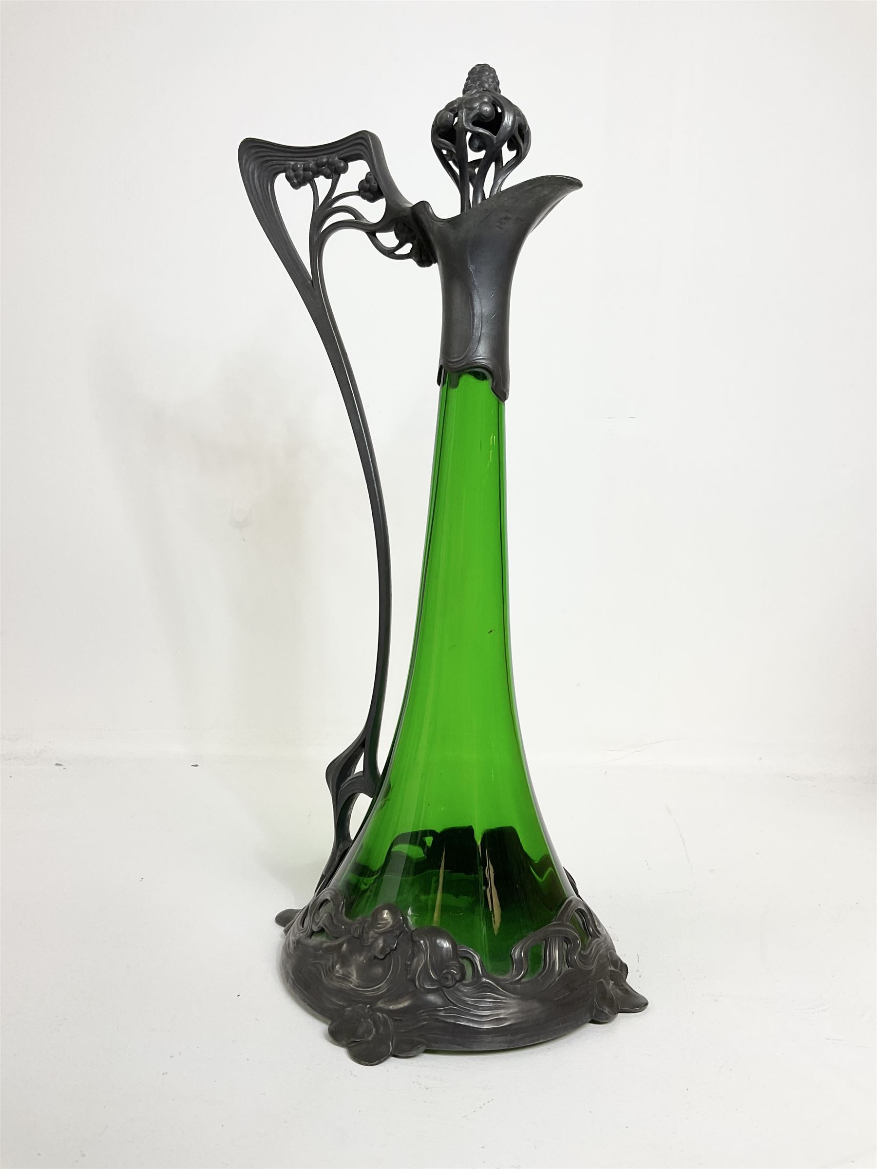 Early 20th century WMF Art Nouveau pewter and green glass ewer, of swept cylindrical form, having a pierced stopper and handle of entwined stems and berry design, the base cast as water nymphs with flowing hair and lily pads, H38cm