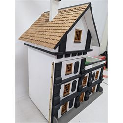 1:24 scale four-storey tudor-style dolls house, with black and white exterior, balcony garden, glazed panelled windows and wooden shingle roof, with decorated interior and wired fireplaces and lighting, H65cm, W58cm, D31cm, 