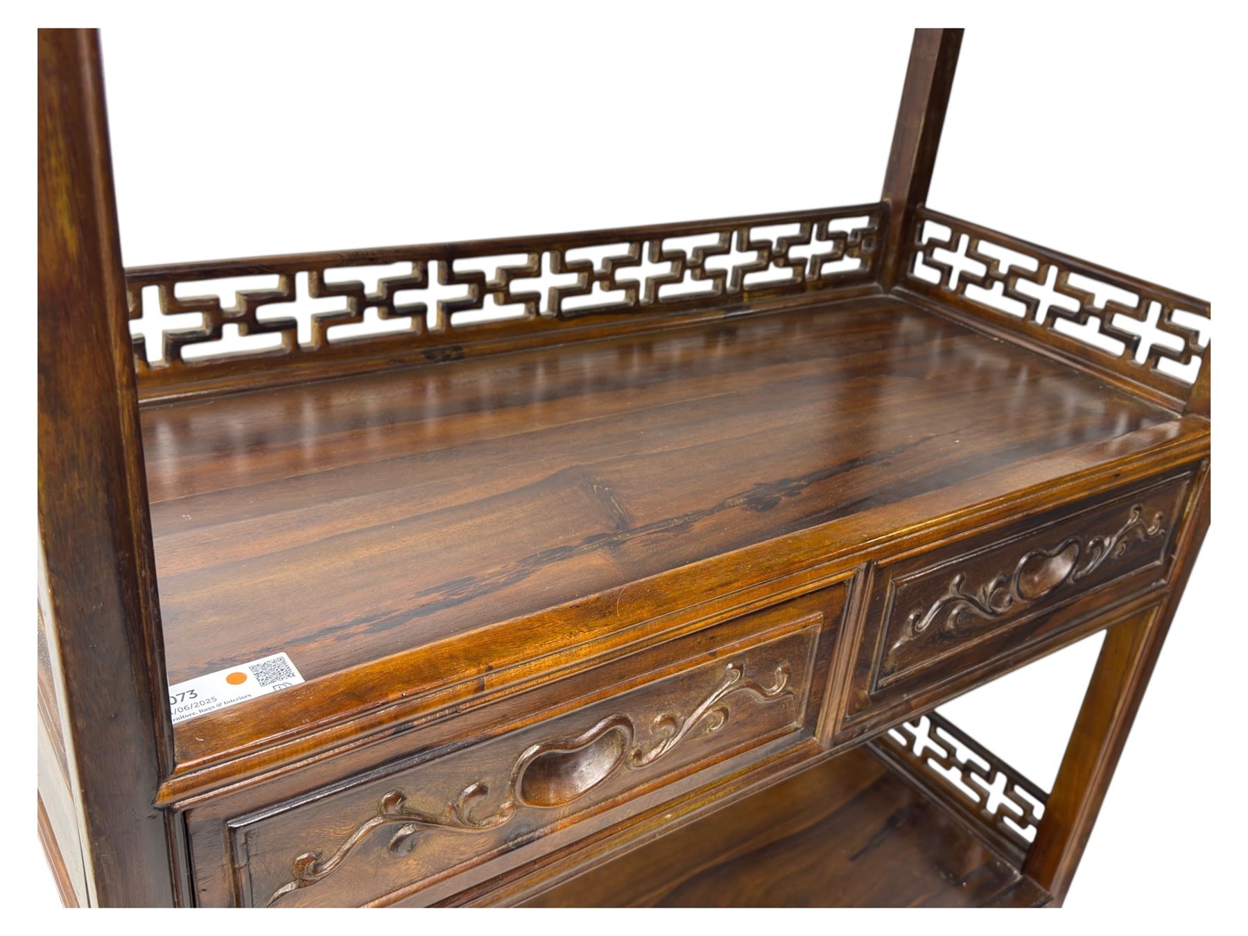 Early 20th century Chinese hardwood display étagère bookcase, the rectangular open tiered frame with pierced frieze and geometric openwork gallery to each shelf, fitted with two short drawers carved with stylised lotus motifs, supported on square uprights with pierced apron and integral gallery rails