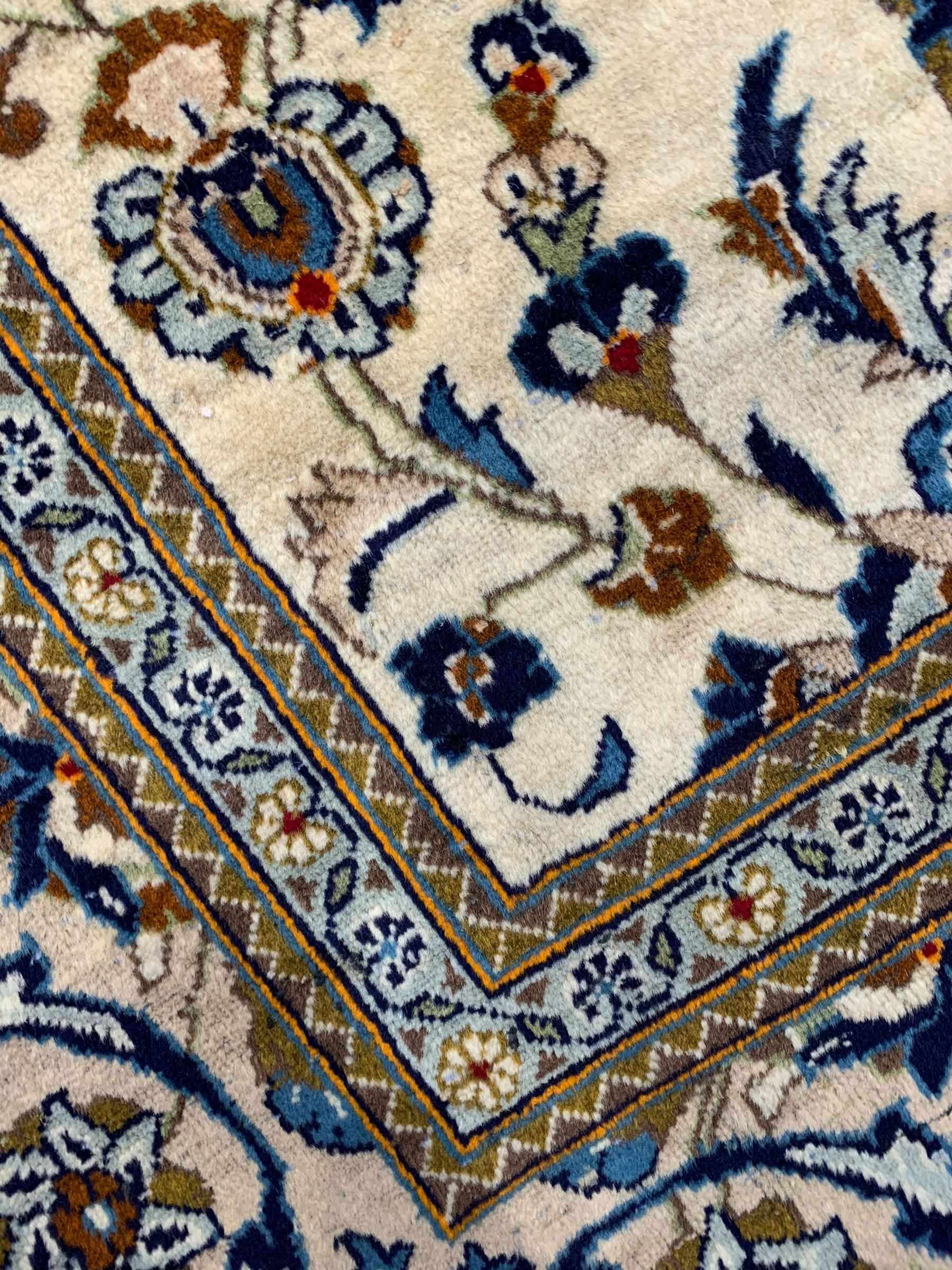 Persian Kashan ivory ground rug, the field decorated with stylised plant motifs and interlacing leafy branches, scrolling border decorated with further plant motifs, floral design guard bands  