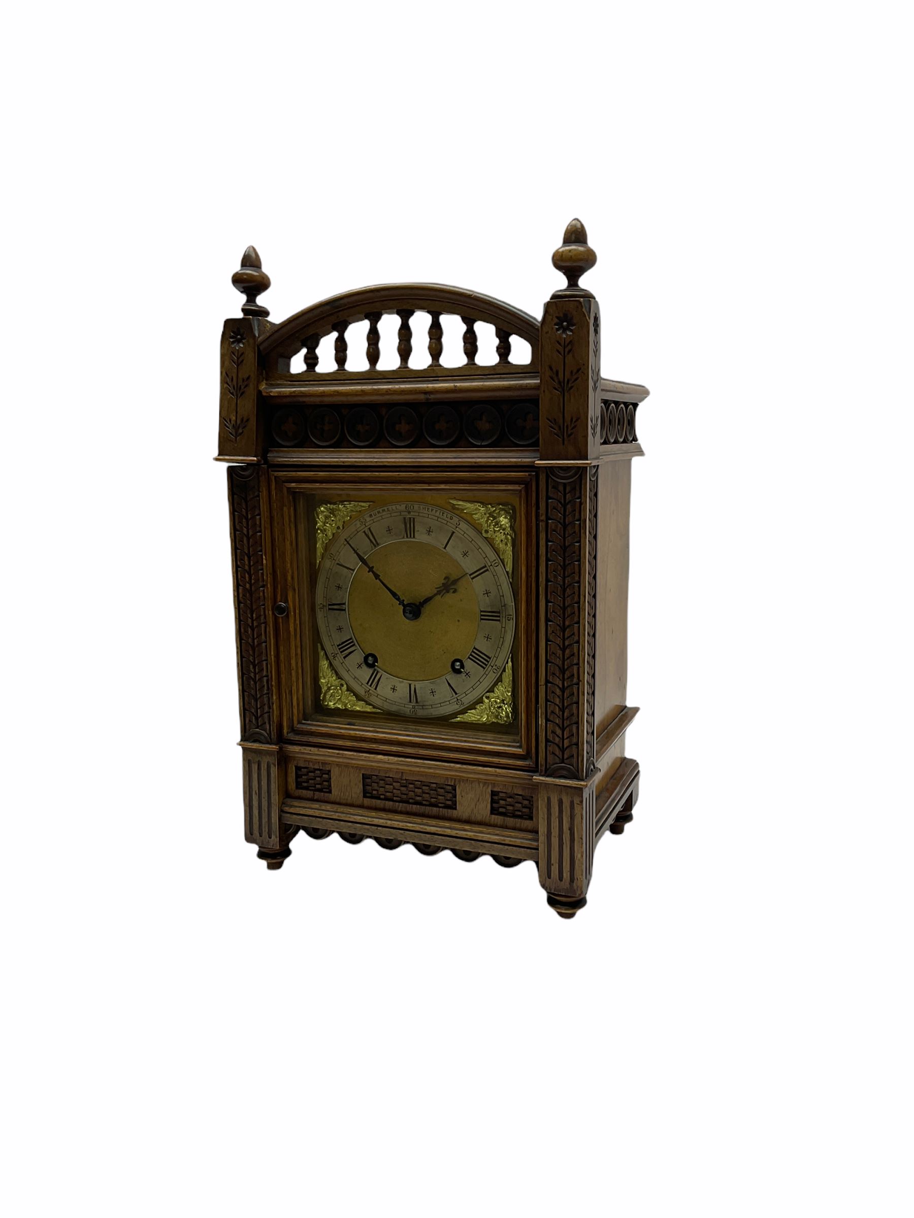 A late 19th century Winterhalder & Hofmeier quarter striking eight-day mantle clock striking the hours and quarters on two coiled gongs, with a recoil escapement and double quarter rack strike, in an aesthetic movement oak case with incised carving, trefoil frieze, raised turned finials and baluster pediment, case door with sound fret, square brass dial, silvered chapter ring with roman numerals, minute track and half hour markers, steel Fleur de Lys hands and cherub face spandrels, dial inscribed “Burrell Sheffield”.
With pendulum & Key.
