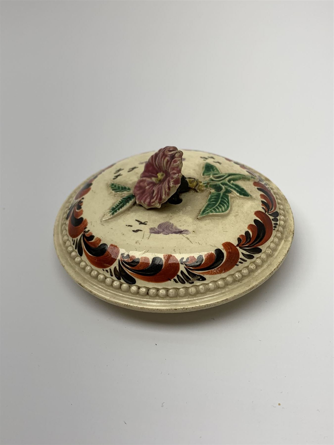 18th century creamware teapot, probably Leeds, with reeded entwined handle and floral finial to the cover, the body with hand painted polychrome decoration of figure to one side, and floral spray to the other, collectors paper label beneath inscribed Leeds Pottery, H11.5cm