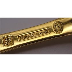 Two Danish silver-gilt year spoons by Georg Jensen, the first example decorated with enamel blue cornflower motif, dated 1972, in original pouch, the second example decorated with enamel pink briar rose motif, dated 1976, in original box, each impressed on underside RA AB, Sterling Denmark, and marked for Georg Jensen, together with two further examples by A.Michelson, the first with orange enamel fan design, dated 1965, impressed on underside A.Michelsen Sterling Danmark, TH, the second with enamel family scene, dated 1973, impressed on underside 925 S A.Michelsen Sterling Danmark, B Spang Olsen, approximate gross weight 6.11ozt (190.4 grams)