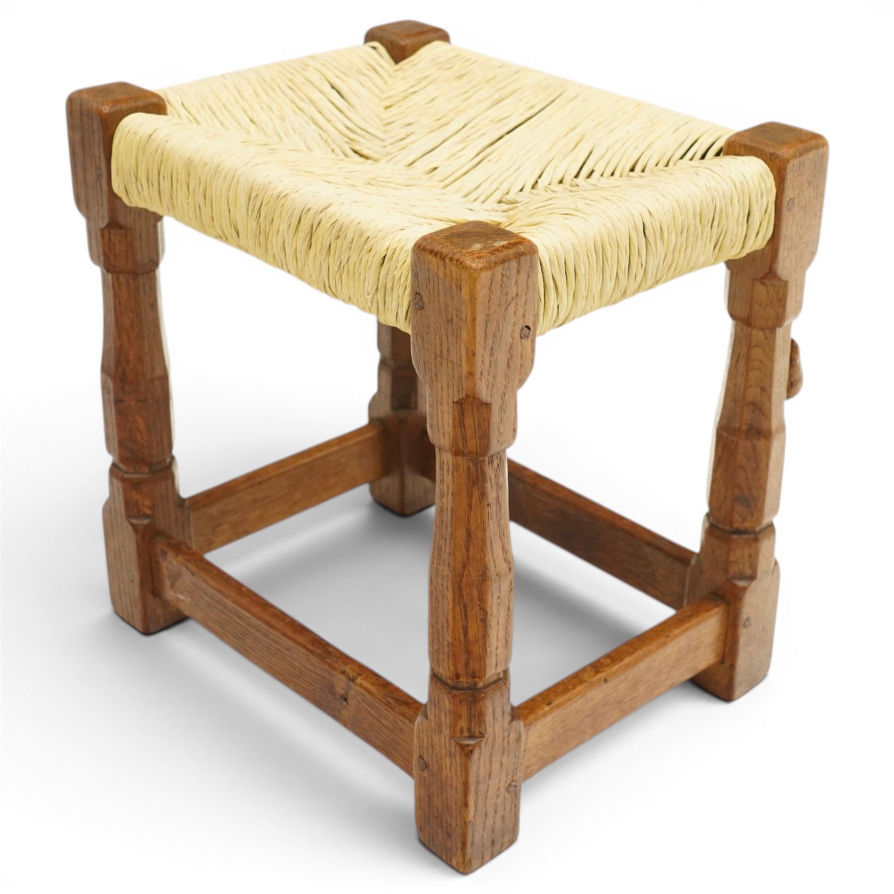 Mouseman - mid-20th century oak stool, the rectangular rush seat raised on turned octagonal supports united by box stretcher, with carved mouse signature, by the workshop of Robert Thompson of Kilburn