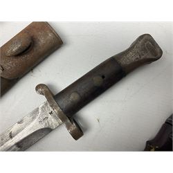 British No 7 MKI knife bayonet with 20cm single edged fullered clipped point blade;  blackened steel, large muzzle ring cross-guard; blackened swivelling pommel marked 'F5H'; red Tufnol composite grips; in blackened steel scabbard L33cm overall; British Pattern 1888 bayonet with scabbard; and German Ersatz bayonet with scabbard (3)