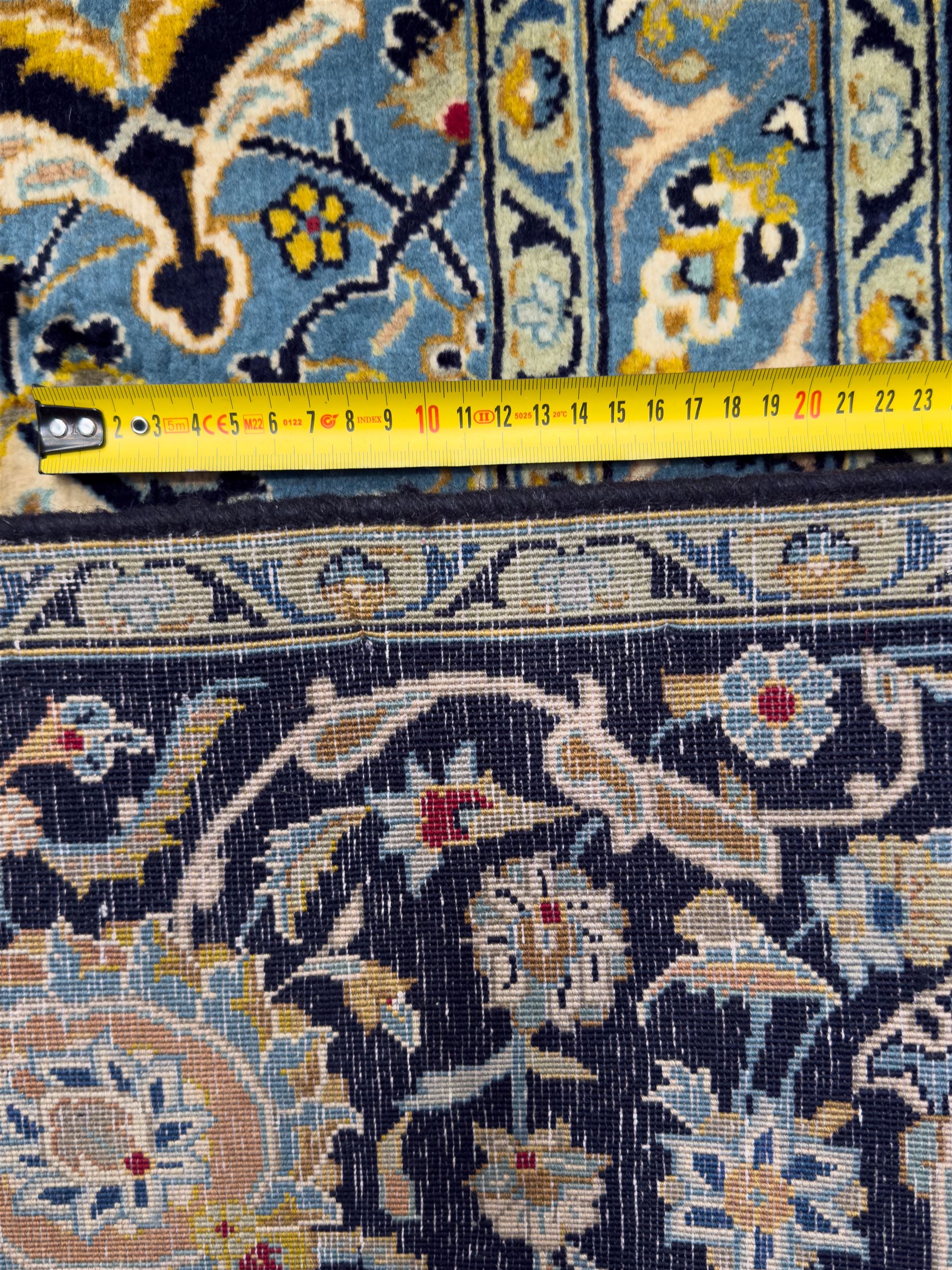 Central Persian Kashan hand-knotted carpet, the navy field with central medallion in pale blue and gold tones, surrounded by spiralling arabesques and palmettes, framed by quarter spandrels and a wide border of stylised lotus and rosette motifs between floral guard stripes, from the region of Kashan