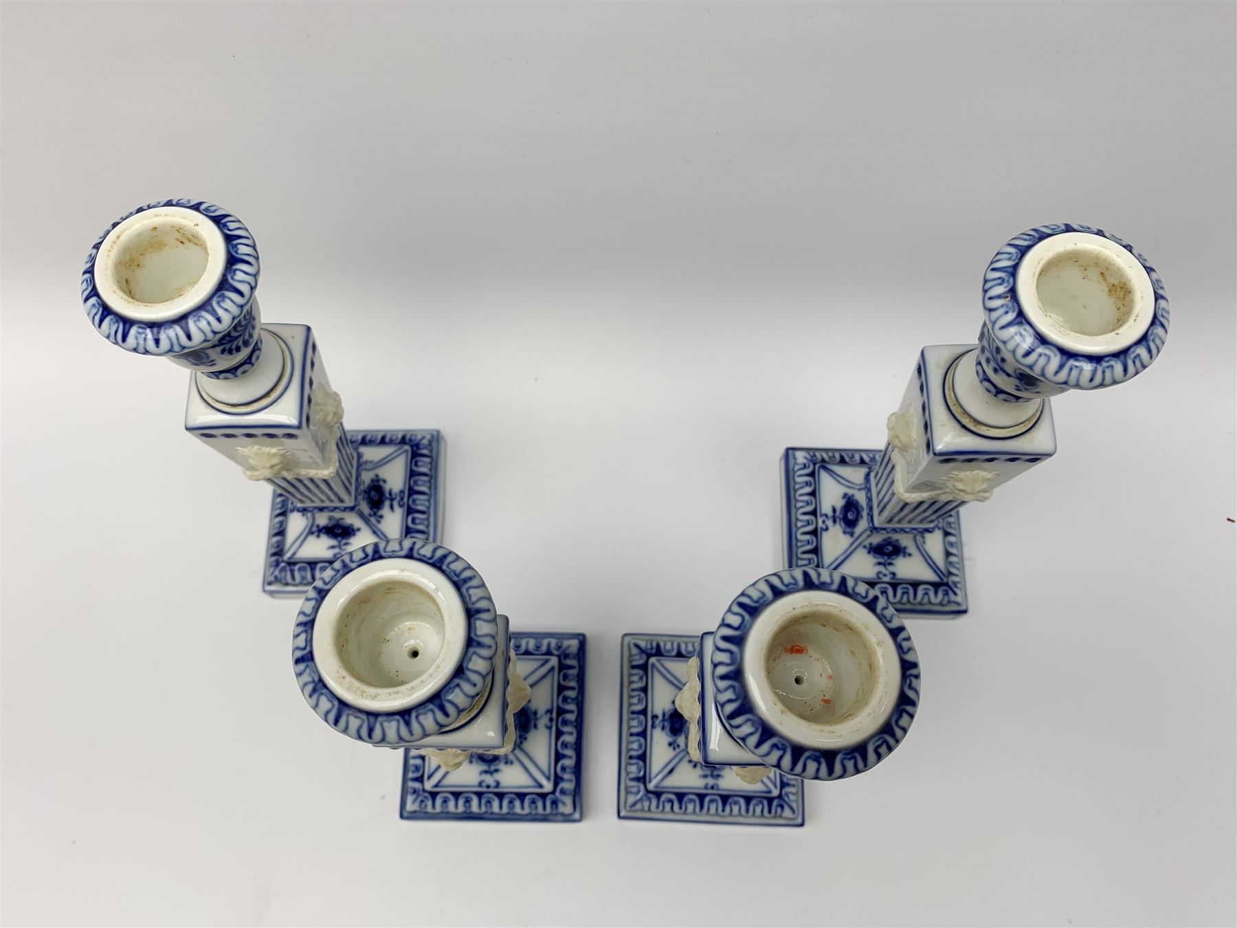 Set of four late 20th century Royal Copenhagen blue fluted candlesticks, of Neoclassical form, the tapering stems with lion masks and husk swag detail, with printed and painted marks beneath, H23cm