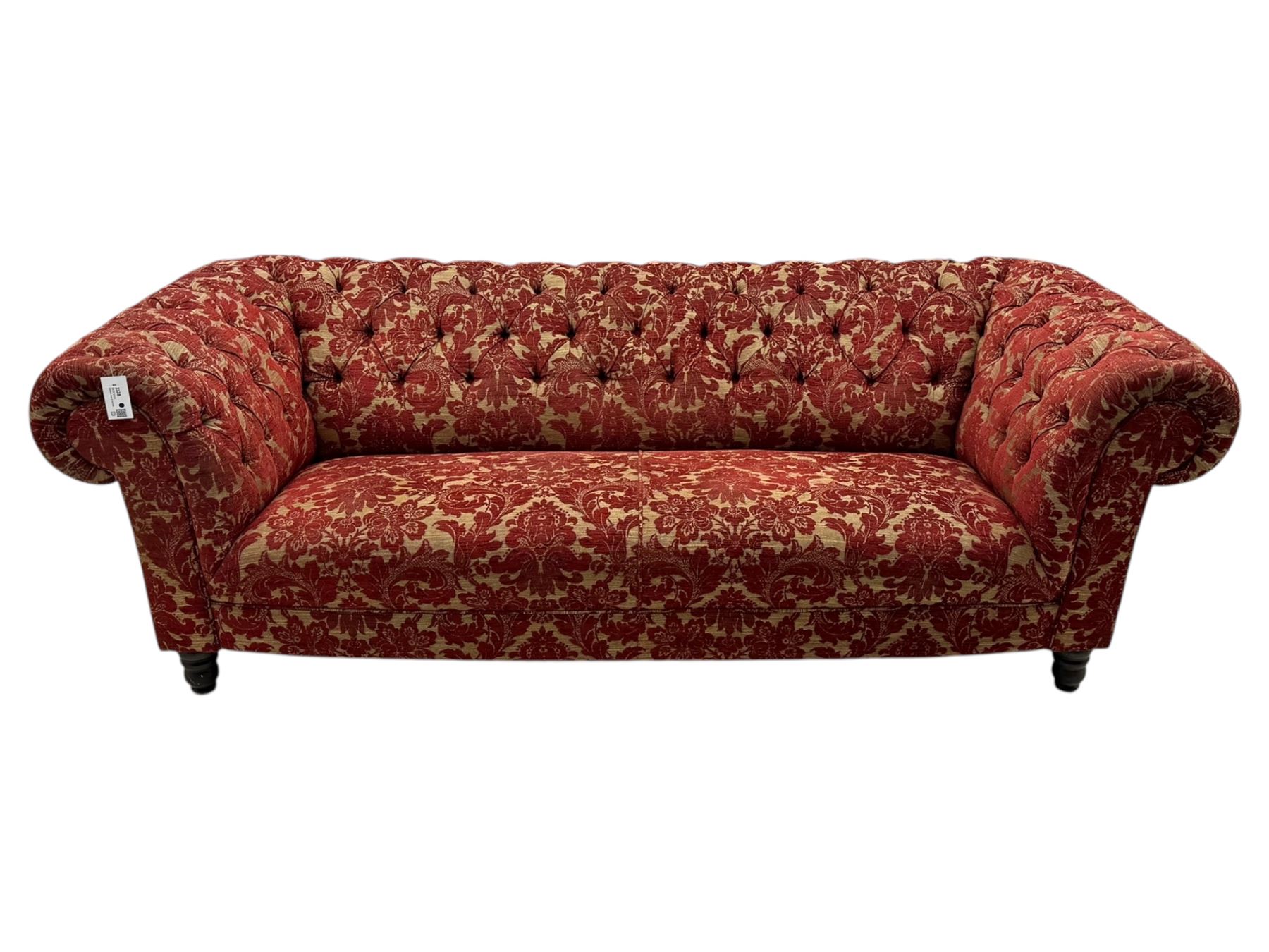 Late 20th century upholstered Chesterfield sofa, in red damask floral fabric, with deep buttoned back and arms, scrolled arms at equal height to back, on turned front supports