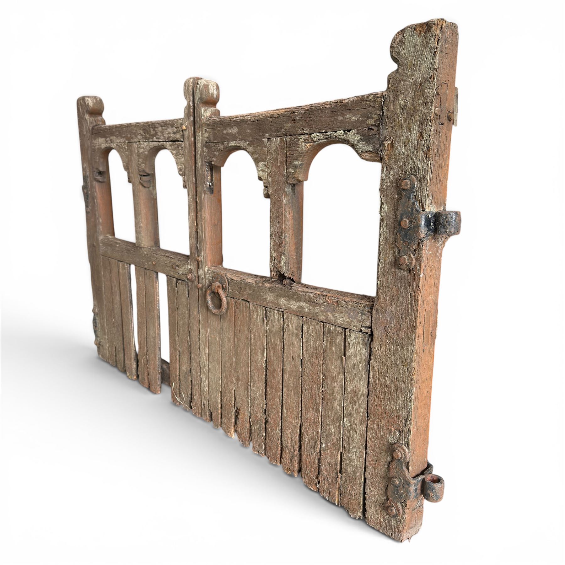 Pair of 19th century weathered wooden ecclesiastical church gates, the cresting rail over four pierced arches with slatted lower section, fitted with heavy cast iron hinges, latch and fittings