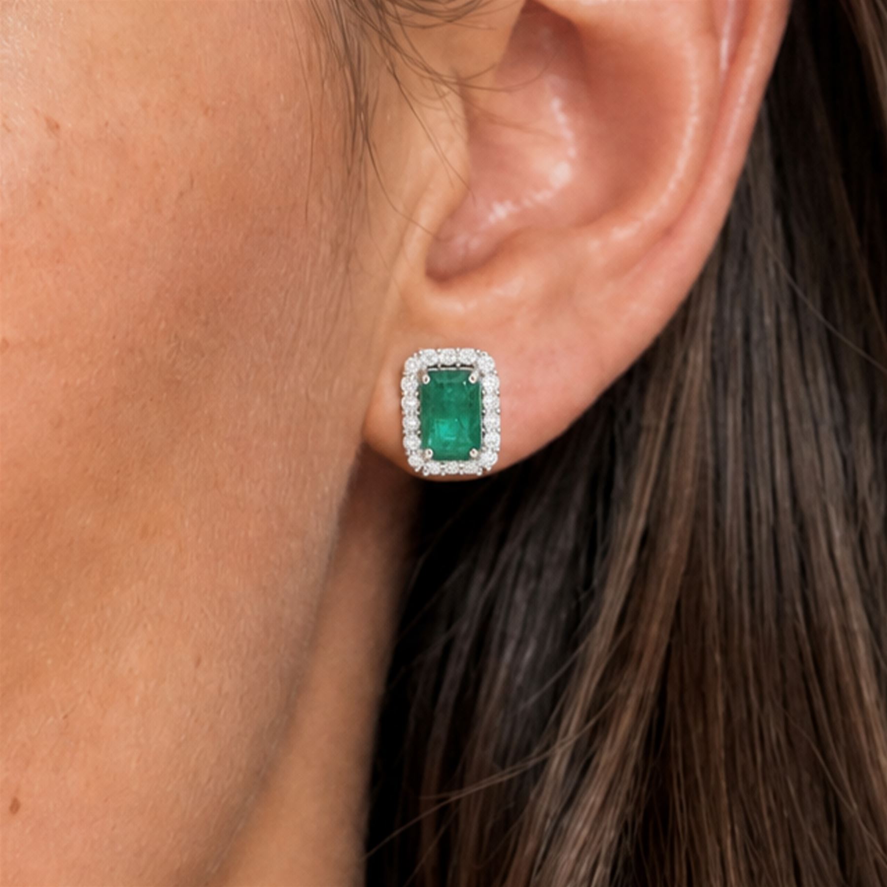 Pair of 18ct white gold emerald and diamond cluster earrings, each stud set with a single octagonal cut emerald, with round brilliant cut diamond surround, stamped, total emerald weight approx 3.00 carat