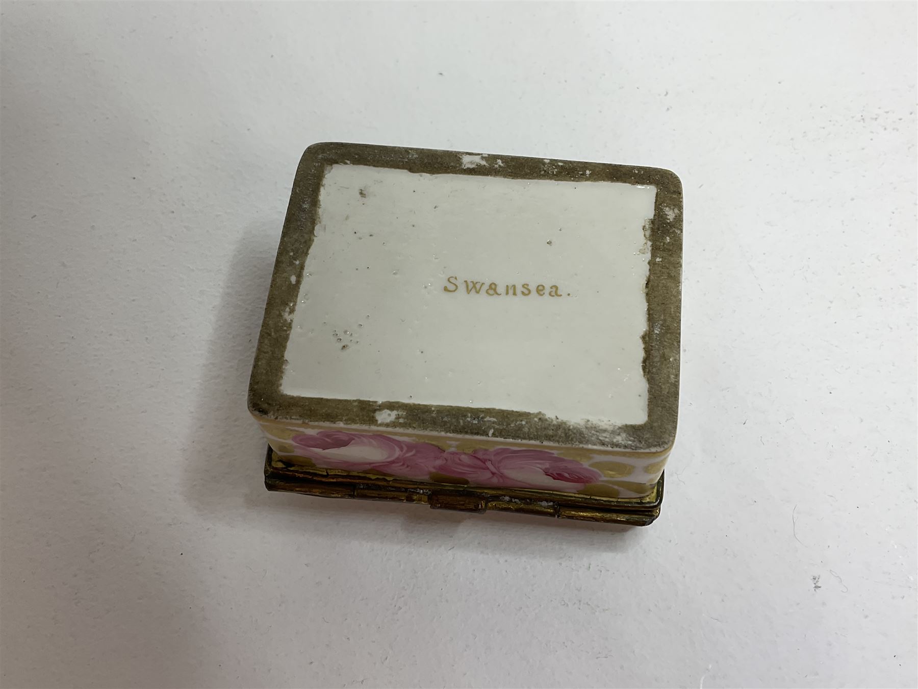 Early 19th century Swansea box of rectangular form, densely decorated with painted pink cabbage roses and gilt foliage upon plain ground, the hinged lid opening to reveal interior painted with two further roses upon plain ground, marked Swansea. in gilded lettering beneath, W7cm H3.5cm D5.5cm