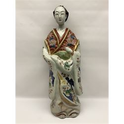 Large Japanese Imari porcelain figure, modelled as a Bijin, wearing a long kimono decorated with apple blossom and leafy branches on a white ground, with gilt detailing, possibly Edo period, H63cm