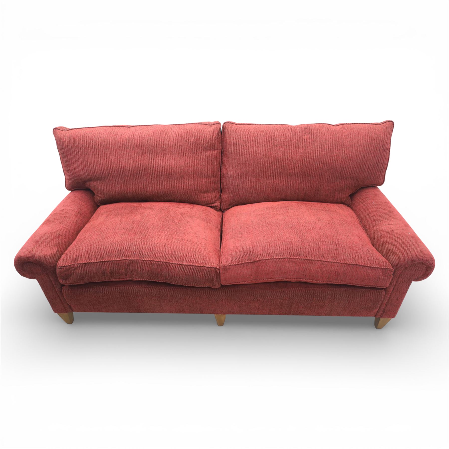 Late 20th century three seat sofa upholstered in red fabric, with gently rounded scroll arms, loose seat and back cushions, raised on tapered wooden legs
