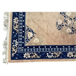 Chinese washed woollen peach ground rug, indigo borders and trailing foliate decoration, central medallion decorated with flowerheads 