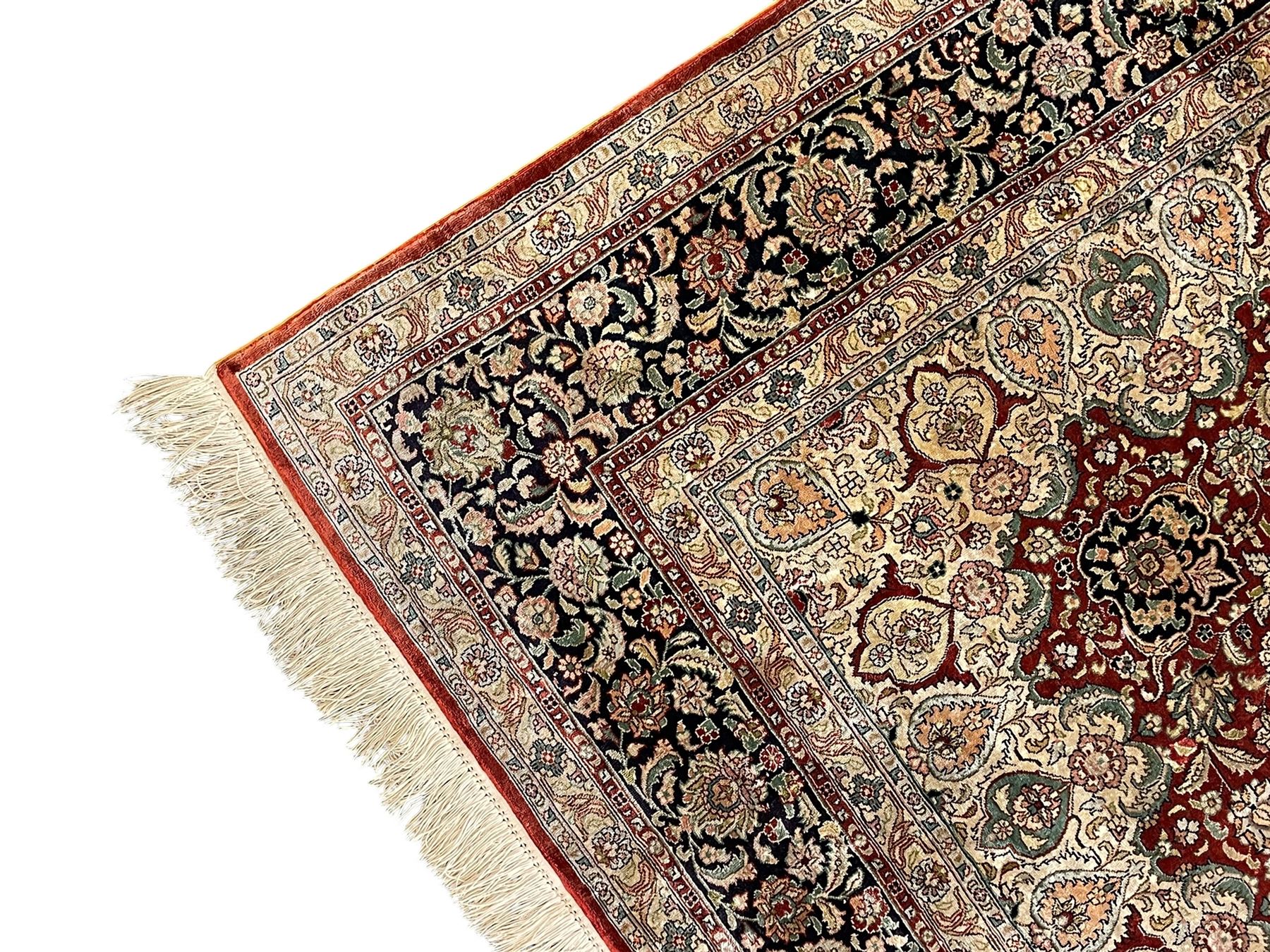 Persian silk finely knotted rug, central floral rosette medallion surrounded by curling branches decorated with palmettes, repeating pattern borders decorated with stylised plants and trailing leafy branches  