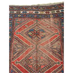 Kurdish crimson ground rug, the field decorated with four lozenge medallions, triple band border decorated with stylised flower heads