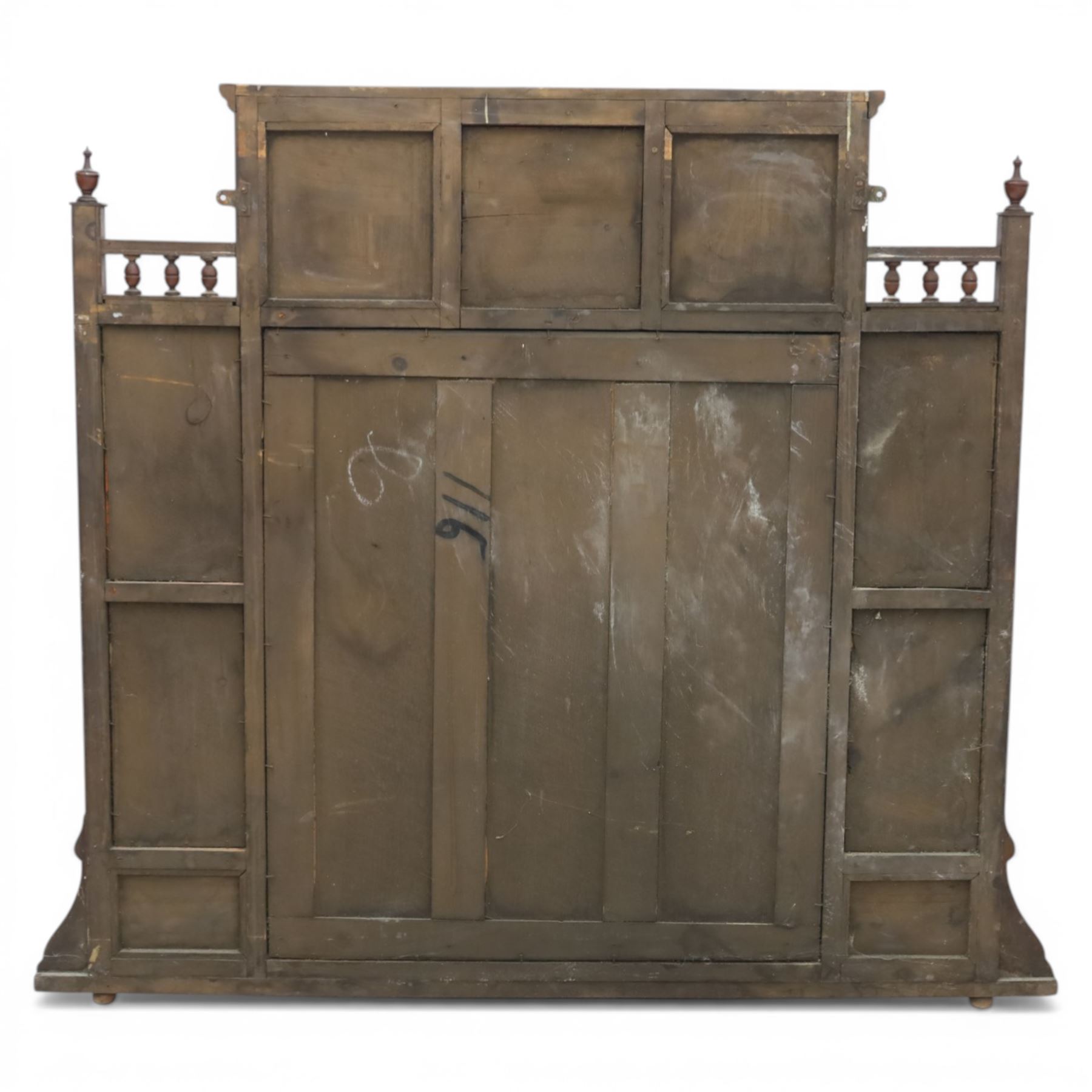 Edwardian walnut overmantel mirror, moulded cornice over three arched apertures with turned supports, flanked by open shelves with turned uprights and finials, carved foliate panels to the base