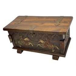 Mid-20th century carved hardwood chest, the rectangular hinged top with decorative strap hinges, the front and sides deeply carved with medieval-style jousting knights, heraldic shields, and architectural elements, raised on shaped block feet