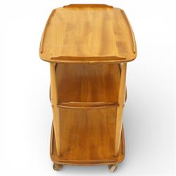 Ercol - elm tea trolley, Model 458. Rectangular three-tier form with shaped gallery edges, supported on turned upright supports, raised on castors