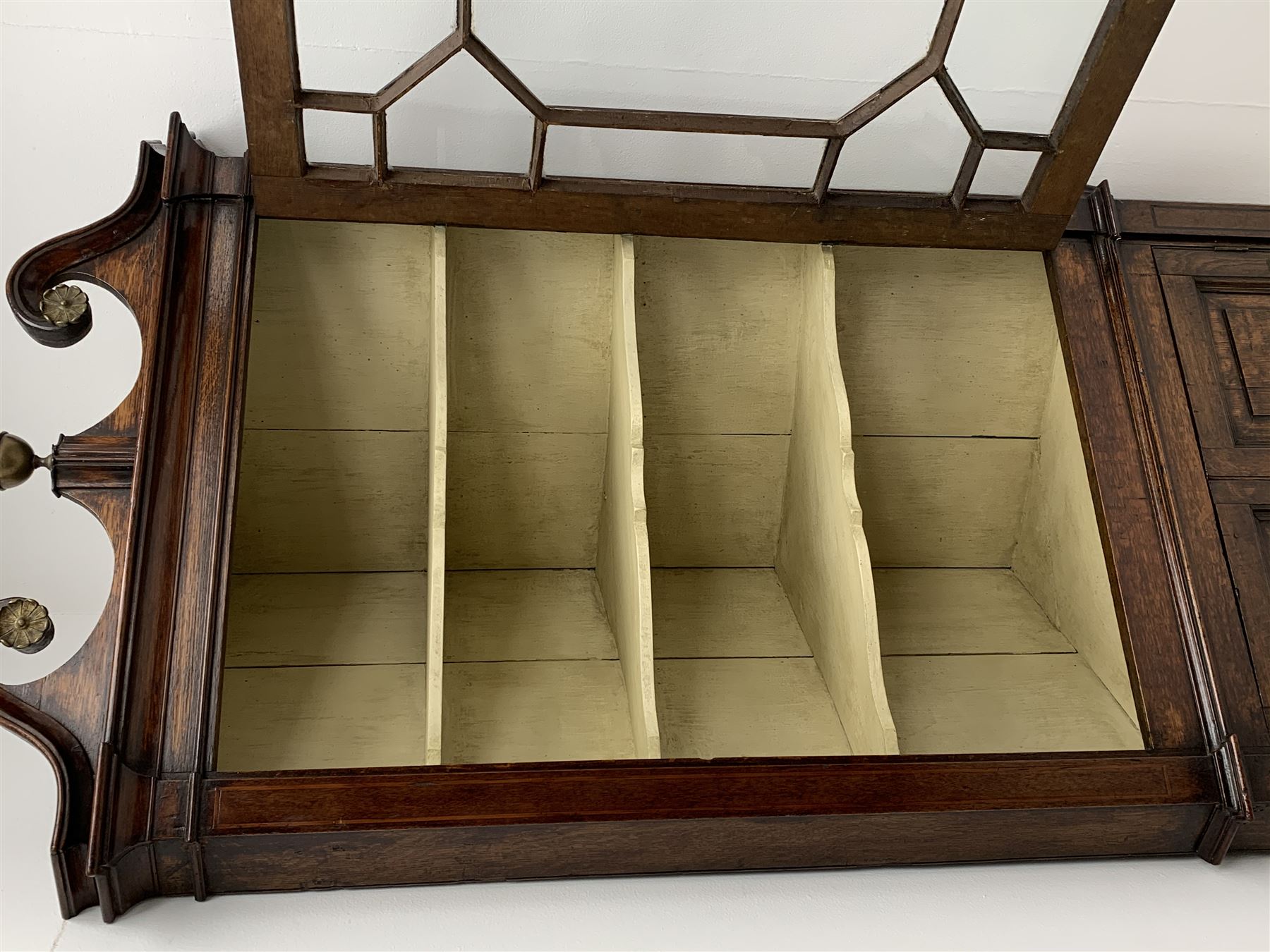 George III oak floor standing corner cabinet, scrolled swan neck pediment with central finial over astragal glazed door, painted interior fitted with three shaped shelves, the lower section fitted with single shaped shelf enclosed by two fielded panel doors inlaid lozenges, on bracket feet, H195cm, W77cm