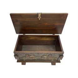 Mid-20th century carved hardwood chest, the rectangular hinged top with decorative strap hinges, the front and sides deeply carved with medieval-style jousting knights, heraldic shields, and architectural elements, raised on shaped block feet
