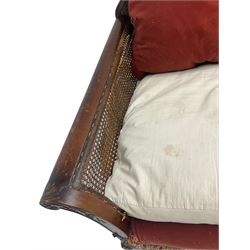 Early 20th century bergère three seat settee, shaped shell carved cresting rail, double caned back and sides, scrolled upright arms and shaped apron carved with shell and foliage, on hairy paw carved feet