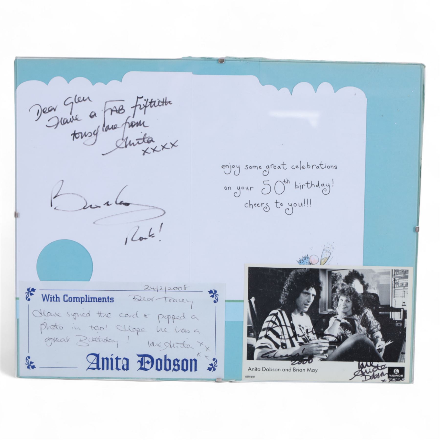 Birthday card and postcard, each signed by Brian May and Anita Dobson, with a personalised Anita Dobson compliment slip dated 2008, in glass frame