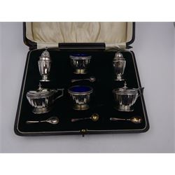 1920s silver six piece cruet set, comprising two mustard pots with covers, two open salts and two pepper pots, all of circular faceted form, mustards and salts with blue glass liners, hallmarked Mappin & Webb, Birmingham 1928, with four matched silver condiment spoons, hallmarked, contained within fitted case 
