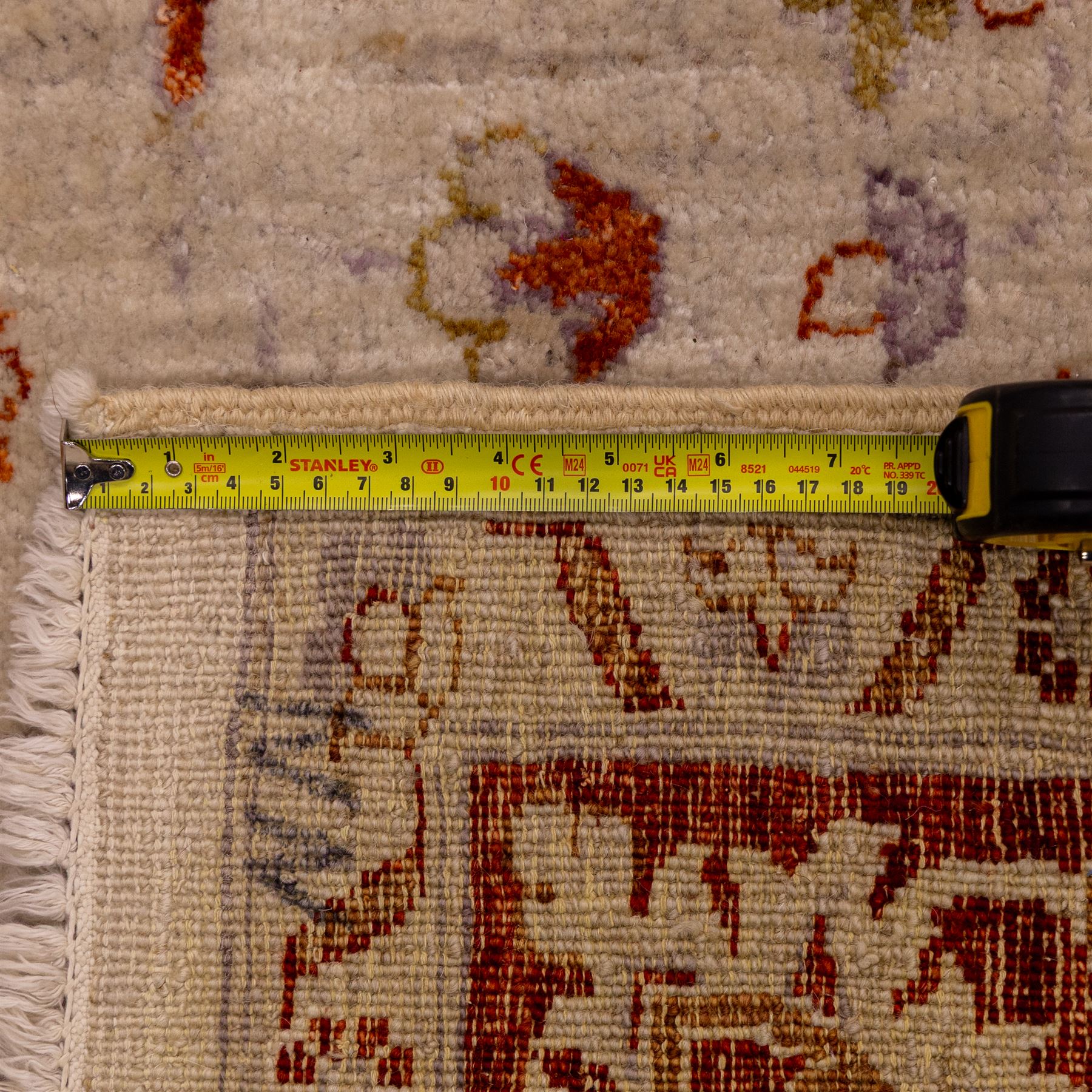 Indian Agra hand knotted rug, the pale beige field decorated with scattered floral sprays and stylised palmettes, enclosed within a wide terracotta border of scrolling foliage and flowerheads between narrow guard bands, finished with fringe ends