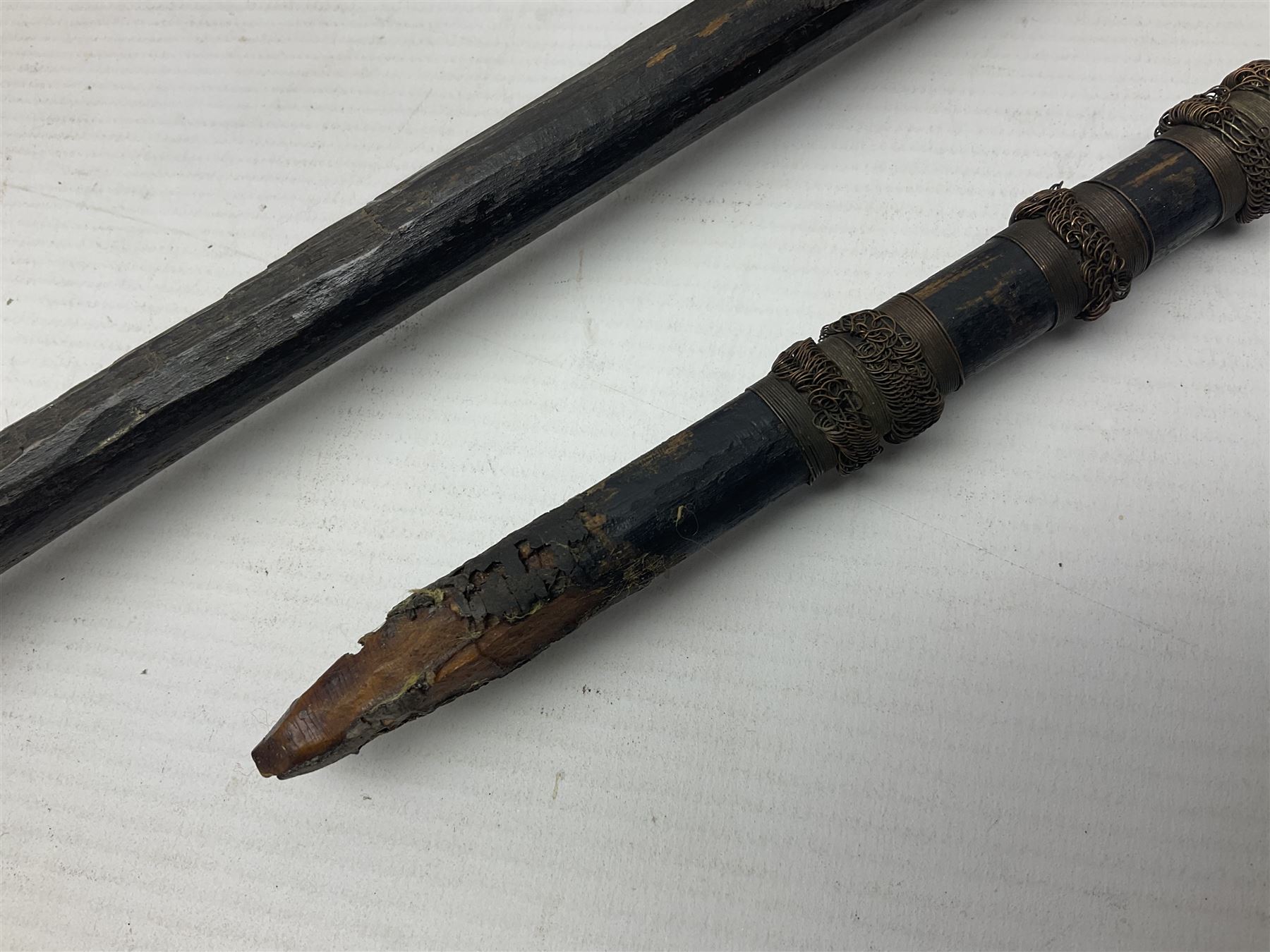 Native hand forged iron fishing spear, the V-shaped head with barbed neck and hewn haft L171cm; and two other hand forged iron spear heads, one with remains of copper bound haft (3)