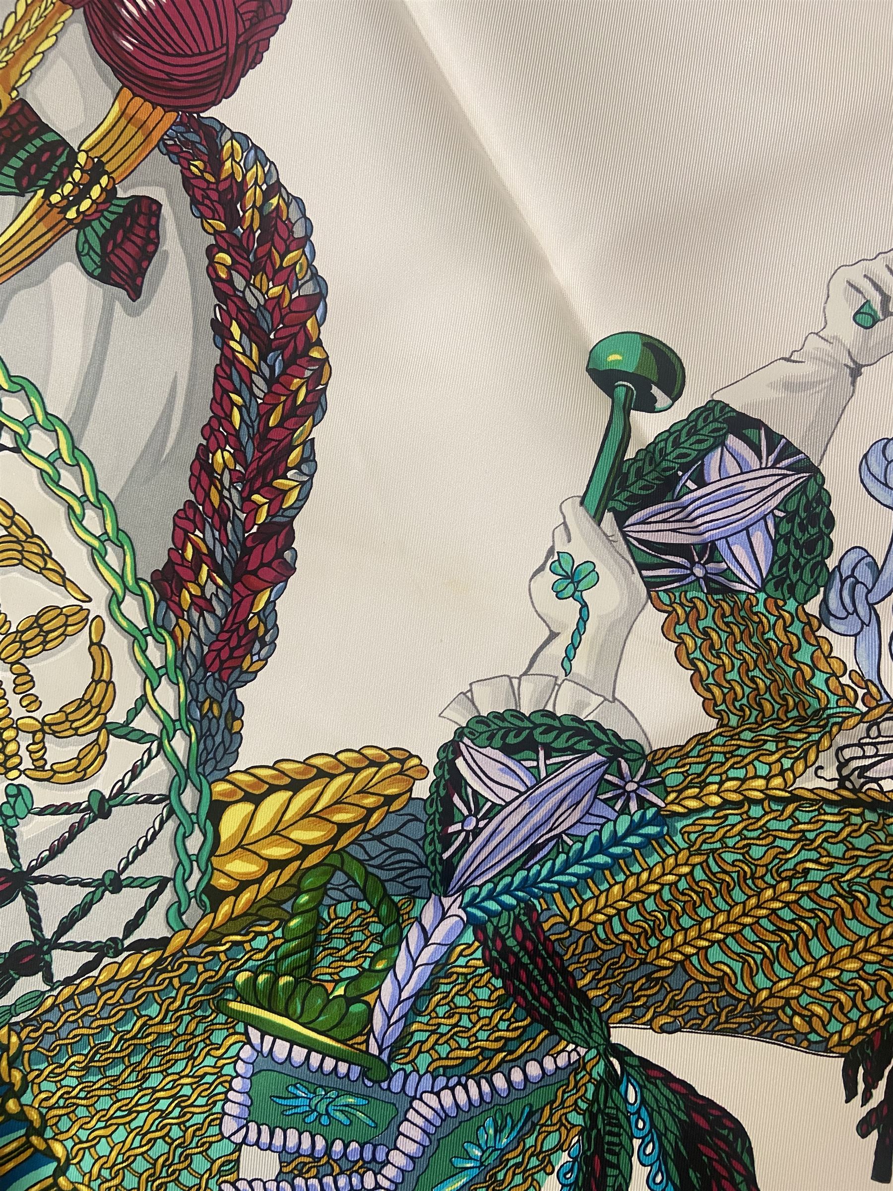 Hermès 'Le Timbalier' silk scarf, designed by Francoise Heron in 1961, printed with a central image of a gentleman on horseback donning extravagant dress, on white ground surrounded with colourful stylised knotted ropes, contained within peacock blue border, with rolled hand stitched edges and Hermes material label, 87cm square