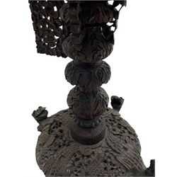 Late 19th century Anglo-Indian carved hardwood occasional table, circular tilt-top carved profusely with mythical animals and foliage decoration, pierced and carved with interlaced leafy branches, leaf carved pedestal supports on a raised platform with further carved and pierced foliage decoration, four carved feet in the form of mythical beasts with gaping jaws 