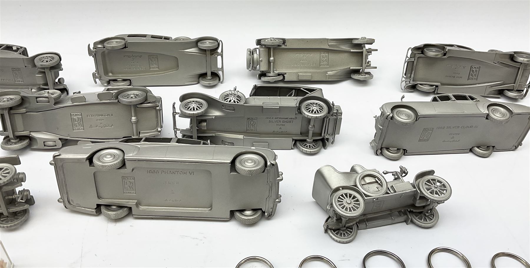 Twelve Danbury Mint pewter models of vehicles including Rolls Royce '1936 Park Ward Baby Rolls', Rolls Royce '1907 The Silver Ghost' etc and a small number of pin badges and car fobs