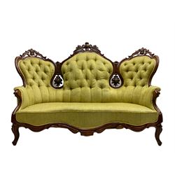 Victorian walnut settee, triple back with pierced and scroll-carved cresting rails over carved fruit and foliage decoration, upholstered in buttoned green fabric, serpentine seat and carved apron, on cabriole feet