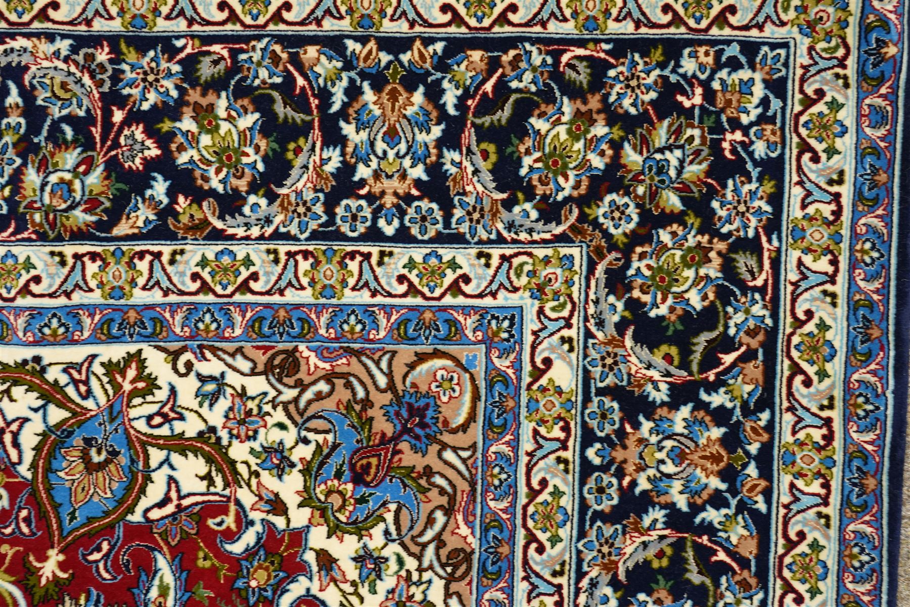 Fine Central Persian Isfahan hand-knotted rug, madder red field with central finely drawn foliate medallion issuing an intricate all-over scrolling vine design with palmettes and arabesques, enclosed by multiple conforming borders in navy ground, signed Isfahan in cartouche, silk fringe ends 