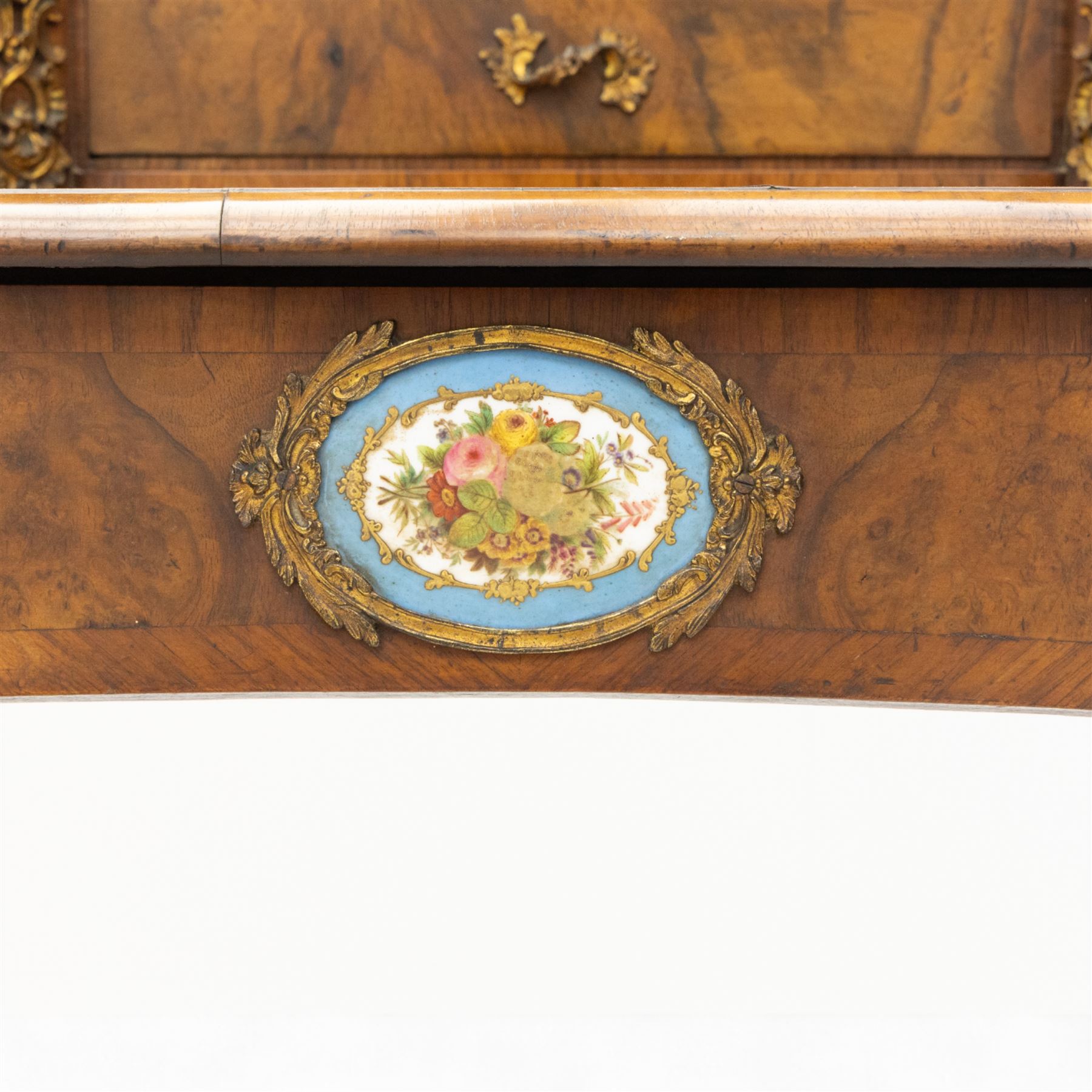 Late 19th-century Louis XV revival gilt bronze mounted and walnut Bonheur-de-Jour, rectangular-shaped serpentine form, with gilt bronze beading, frieze with two blind drawers and gilt bronze handles, centre drawer with large central serves style porcelain plaque, the elevated section with brass gallery above panelled cupboard doors also with serves style porcelain plaques and gilt bronze mounts, interior with single shelf, central section with four drawers each with gilt bronze handles, raised on slender cabriole legs fitted with gilt bronze rococo style masks and sabots