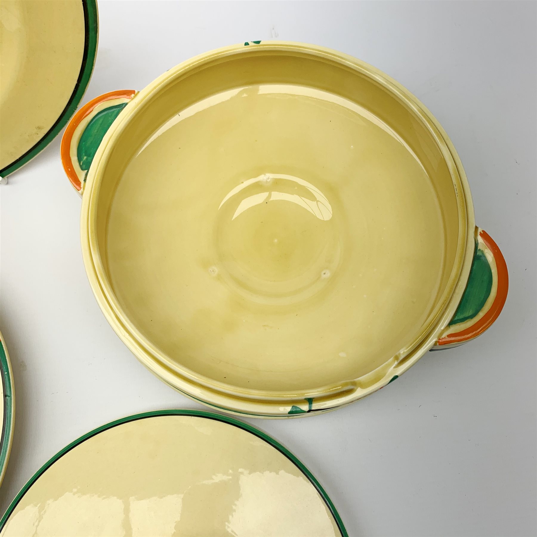 A Clarice Cliff Bizarre by Wilkinson/Newport Pottery vegetable tureen and cover, dinner plate and two dessert plates in the Ravel pattern. (4).